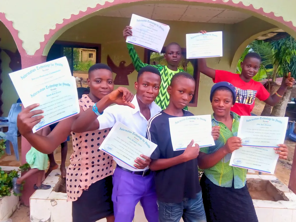 Students hold up their IT4YUS training certificates outside a building