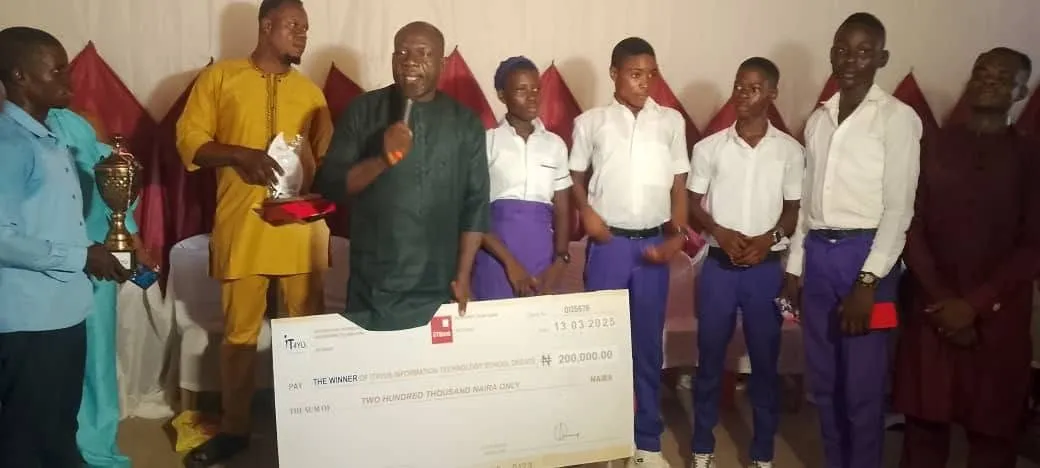 The New Haven Model Secondary School team in purple and white hold the trophy and winners' cheque, 2025