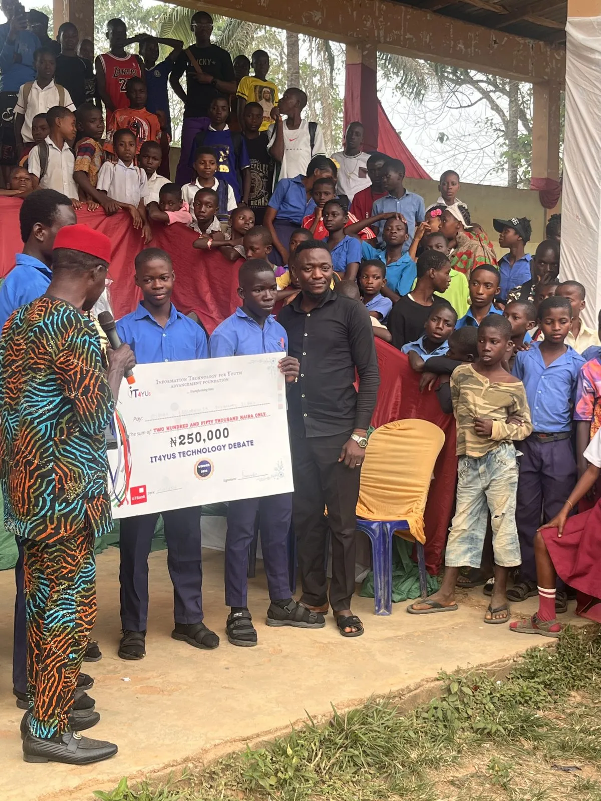 The winning team hold up their cheque as students crowd the stands behind them, 2026