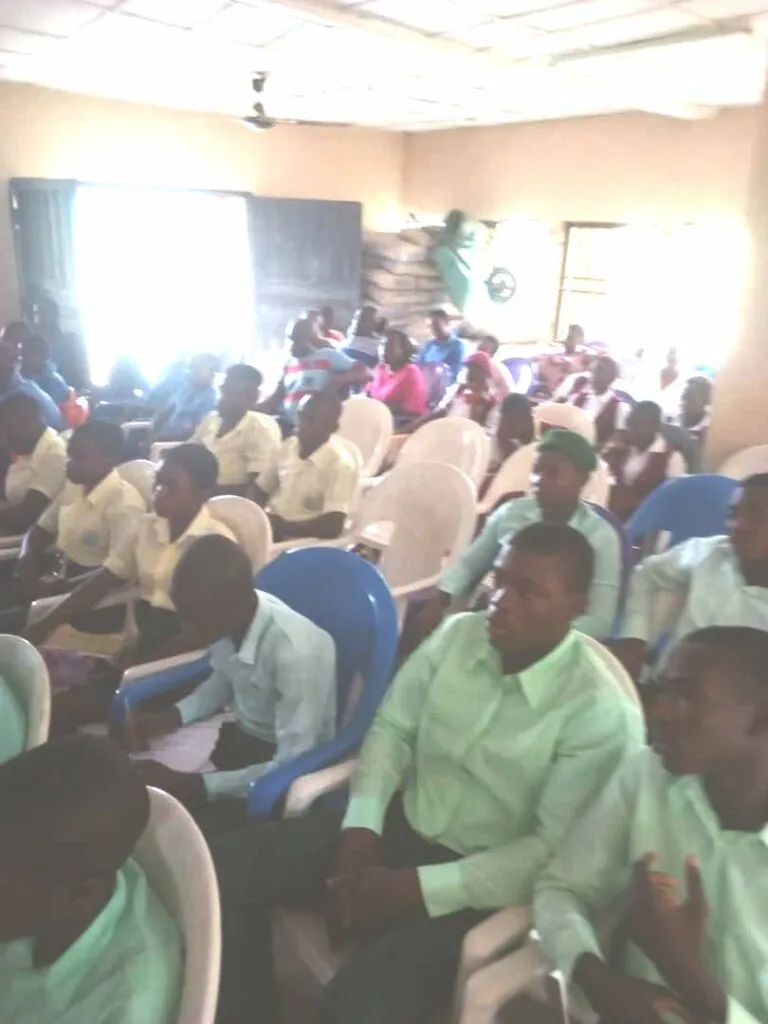 Students in green uniforms fill the hall