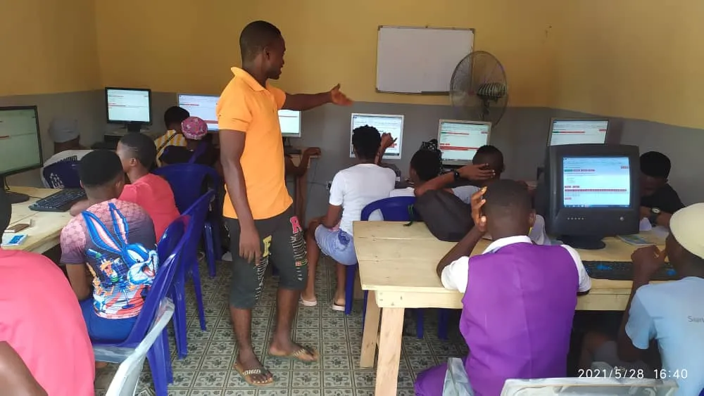 A trainer guides learners at computers during an IT4Uni class