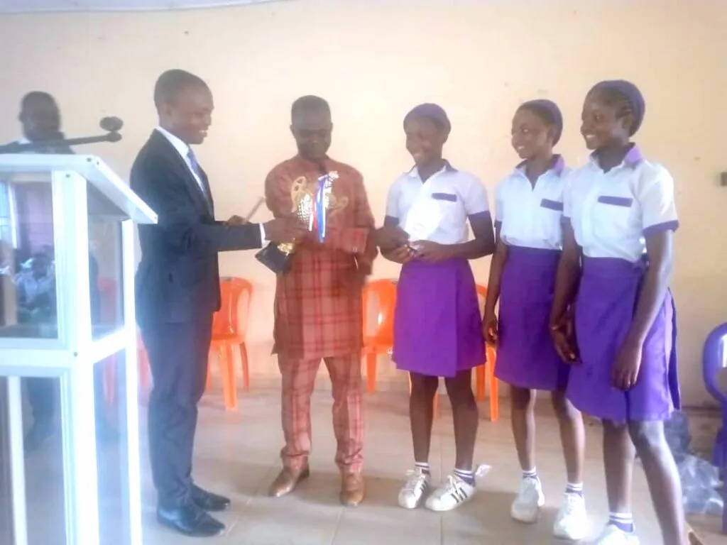 The New Haven Model Secondary School team receive the trophy from a guest