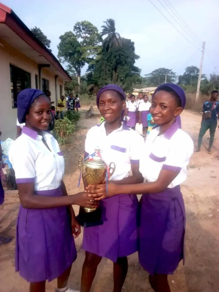 Three New Haven Model Secondary School students hold the 2022 trophy