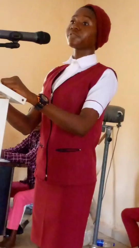 A St. Michael's College speaker in a maroon pinafore at the microphone