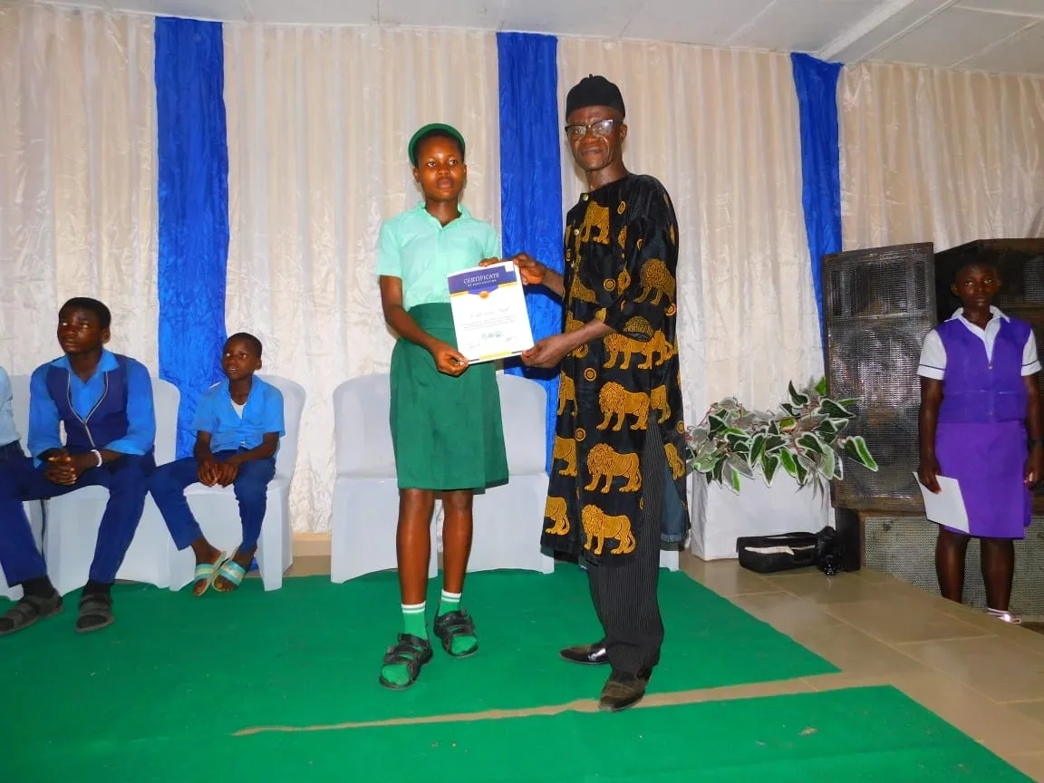 A student in green receives a certificate on stage