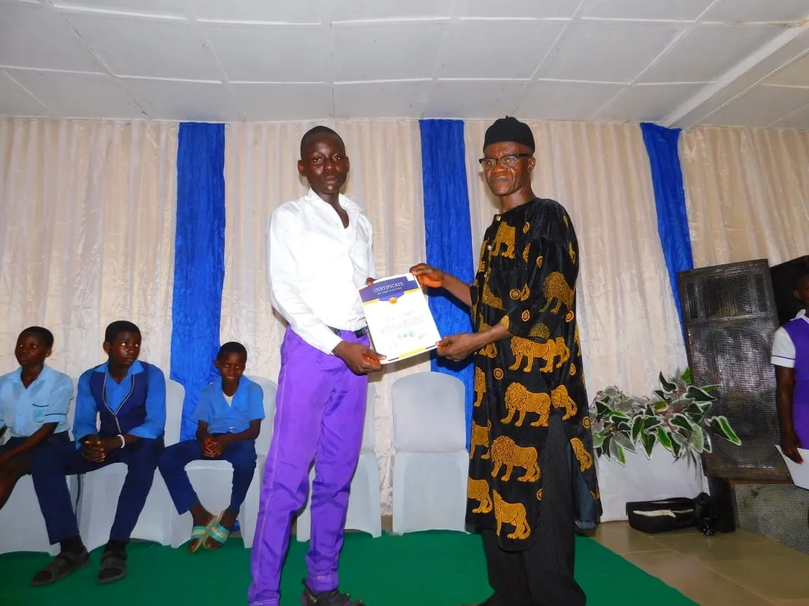 A student receives a certificate from a guest in traditional attire