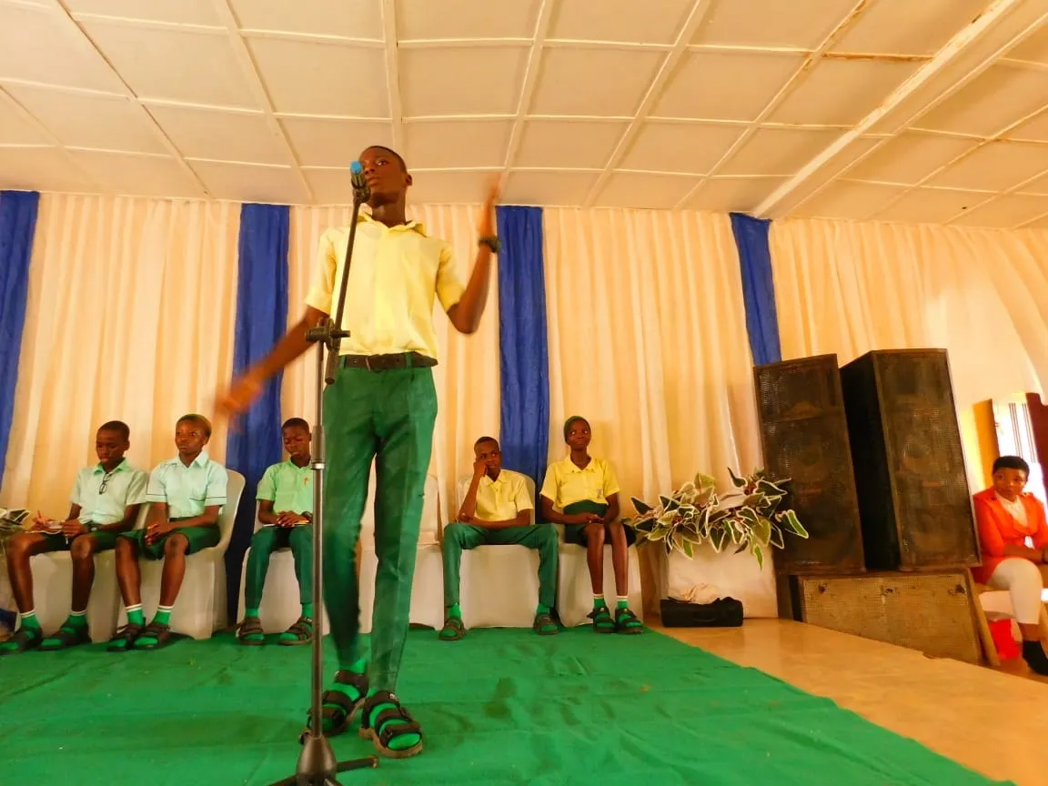 A student speaks with arms open on the debate stage as his team watches