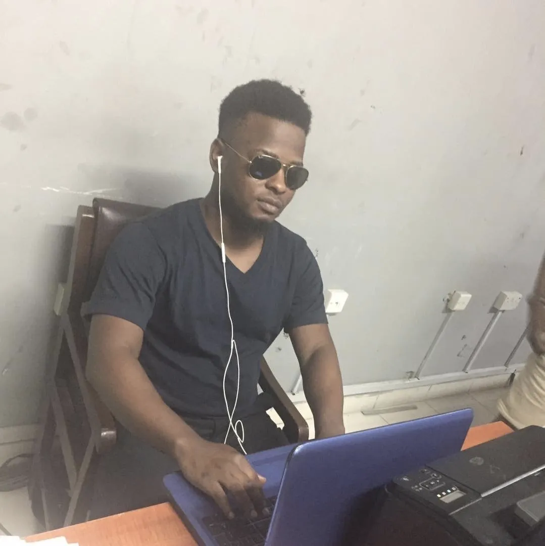 A young man in sunglasses works on a laptop