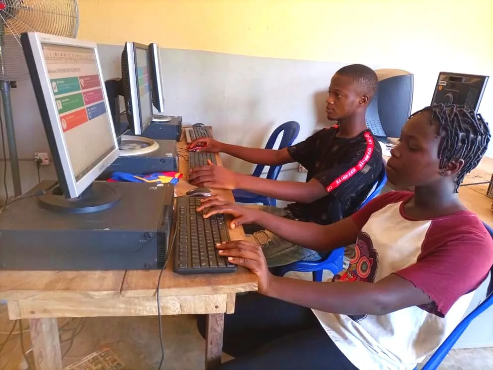 Two students typing at desktop computers during a JAMB CBT training class