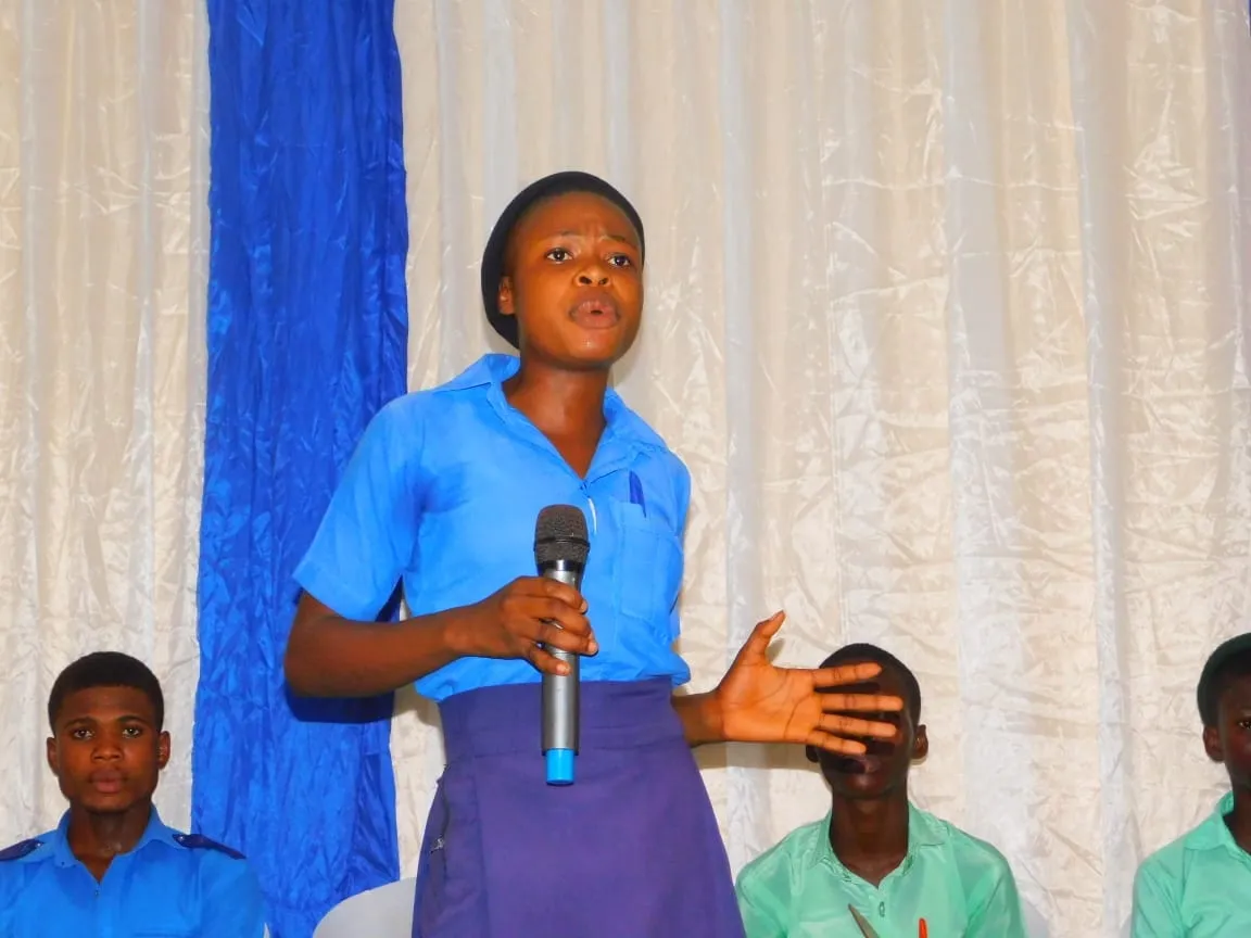 A student in a blue uniform makes her point into the microphone