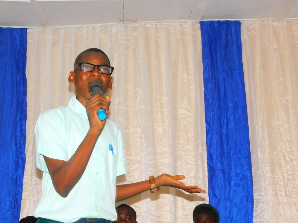 A student in glasses debates into a microphone