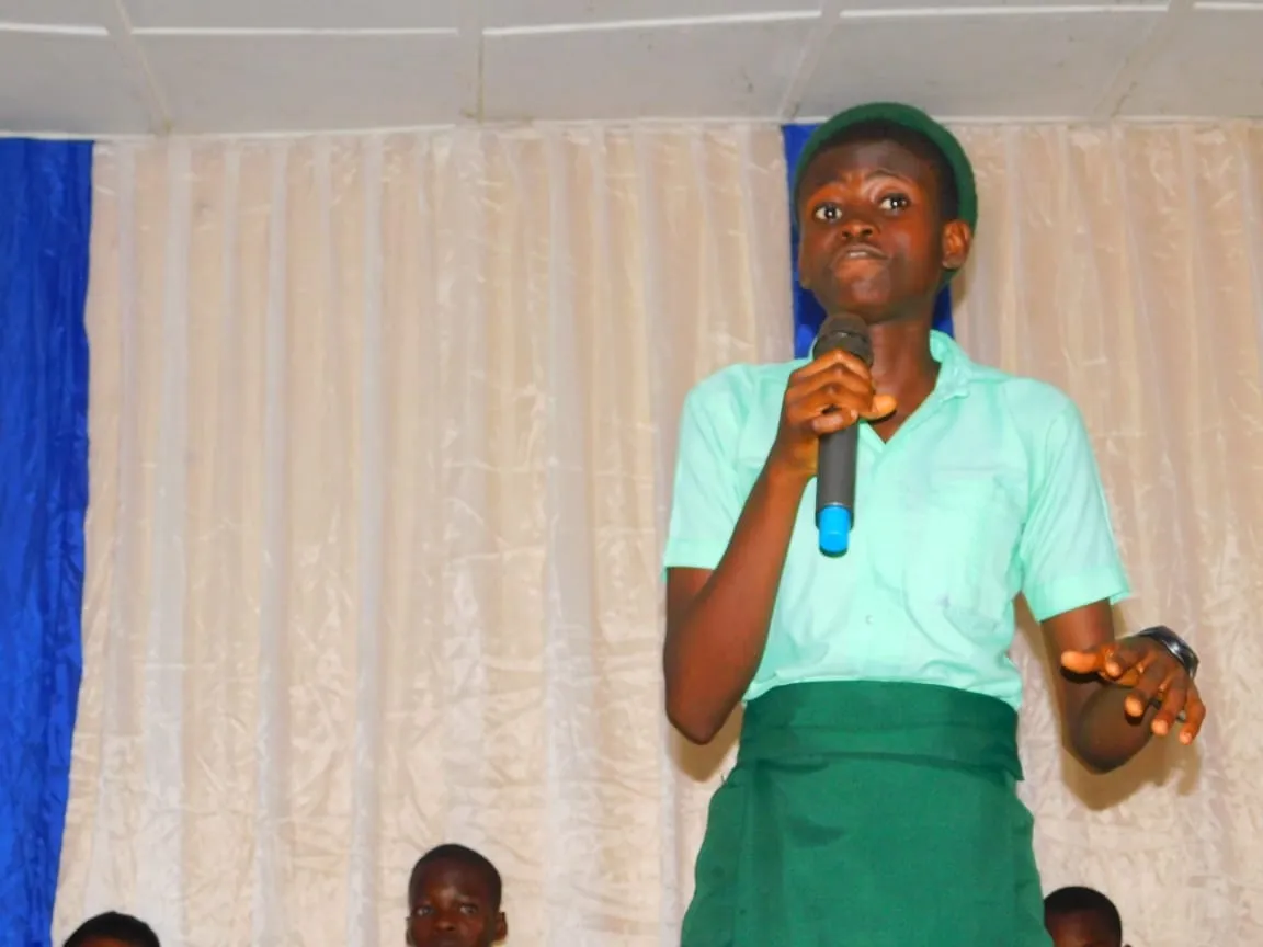 A student in a green uniform speaks at the IT Debate
