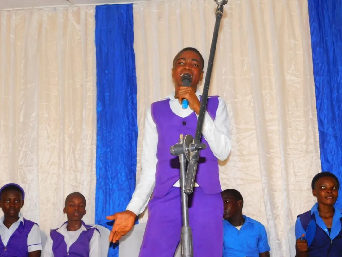 A student in a purple uniform gestures as he speaks at the microphone