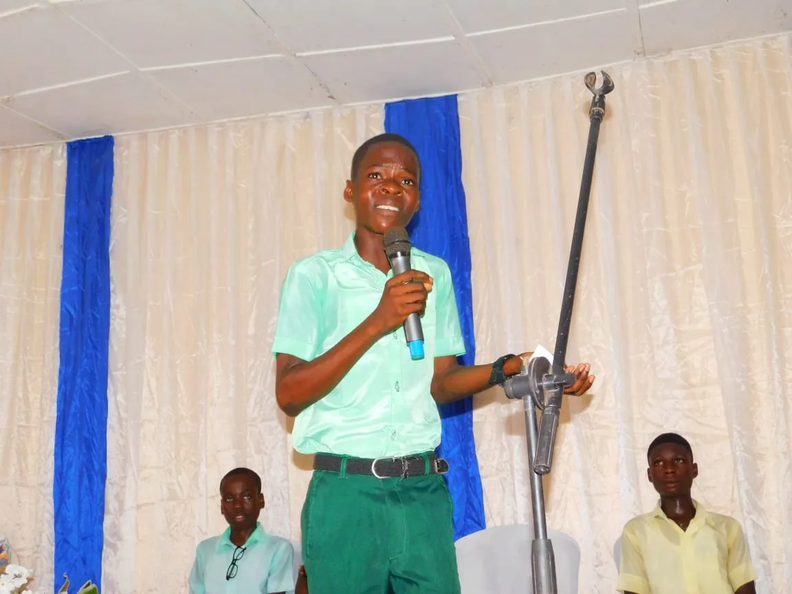 A smiling student holds the microphone during his speech