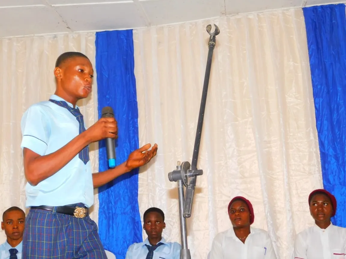 A student in a tie makes his argument on stage